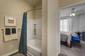 A bathroom with a shower and a bedroom with a bed